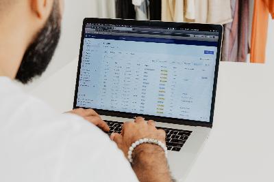 a man works on a laptop computer on a type of spreadsheet or customer service software