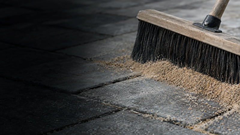 Sweeping polymeric jointing sand into the joints between concrete pavers